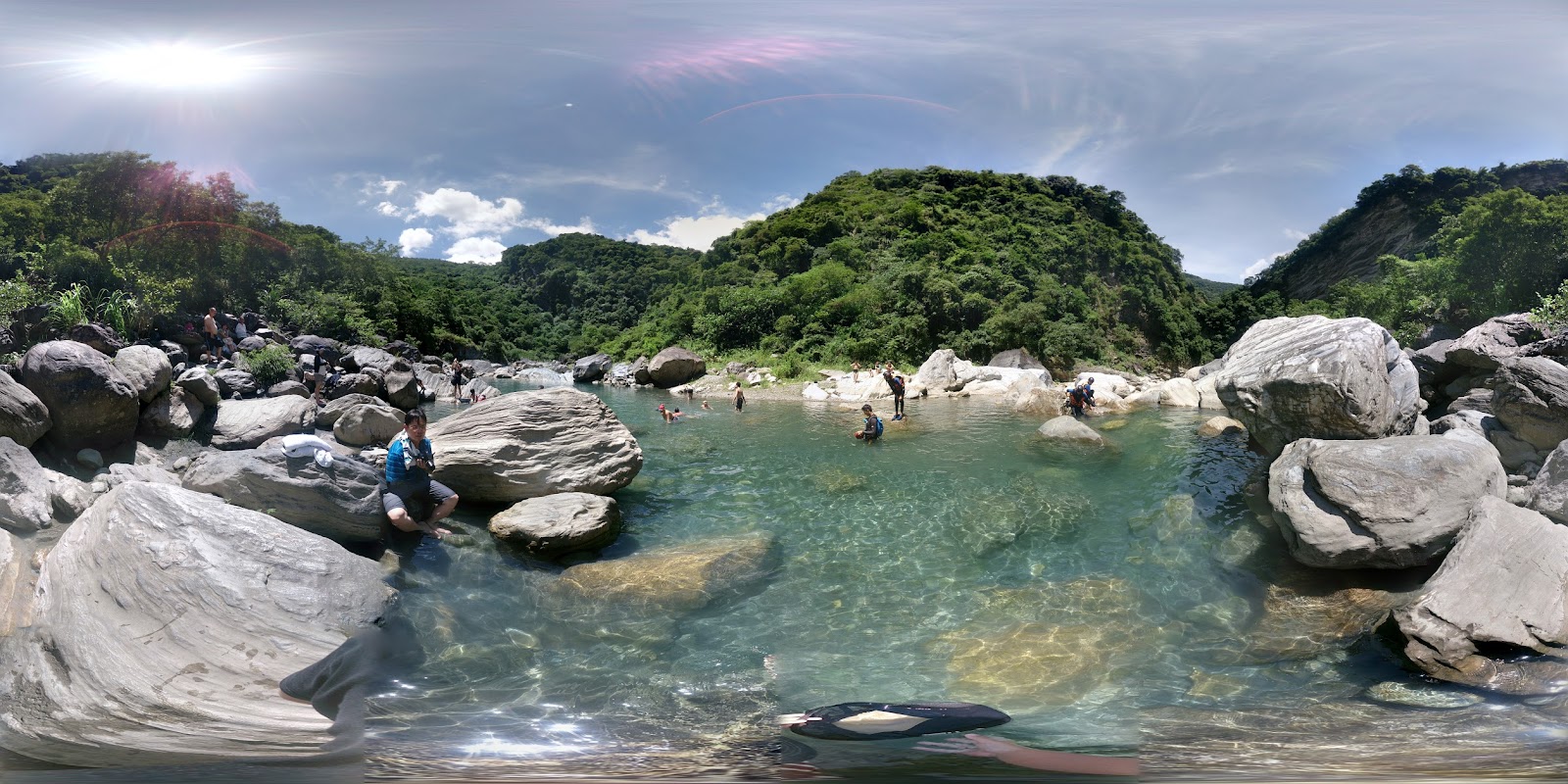 慕谷慕魚遊客在清澈溪谷中戲水，白色礁石與藍天綠山