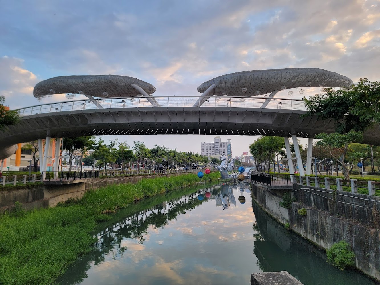 造型獨特的橋樑橫跨河道,兩旁綠意盎然。