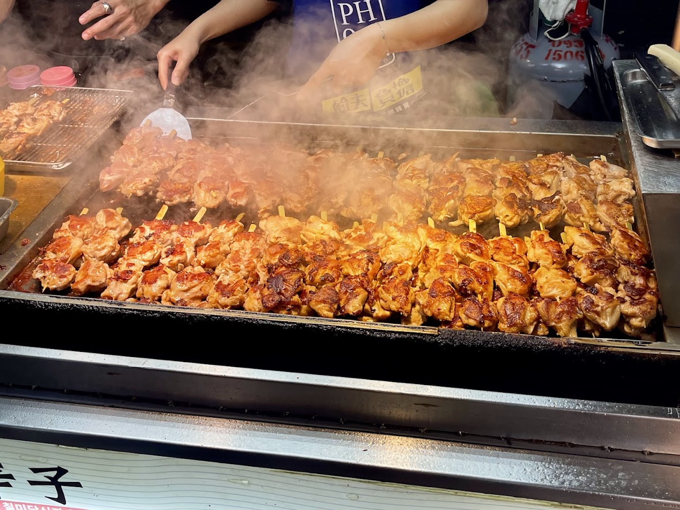 鐵板上烤雞肉串與料理煙霧