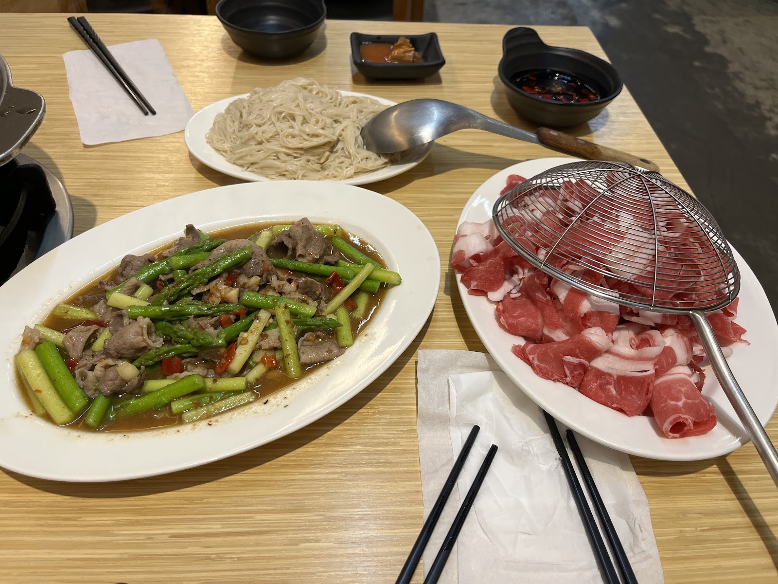 溪湖阿秀羊肉爐桌上菜色,蘆筍炒羊肉、薄切生羊肉盤與手工麵條