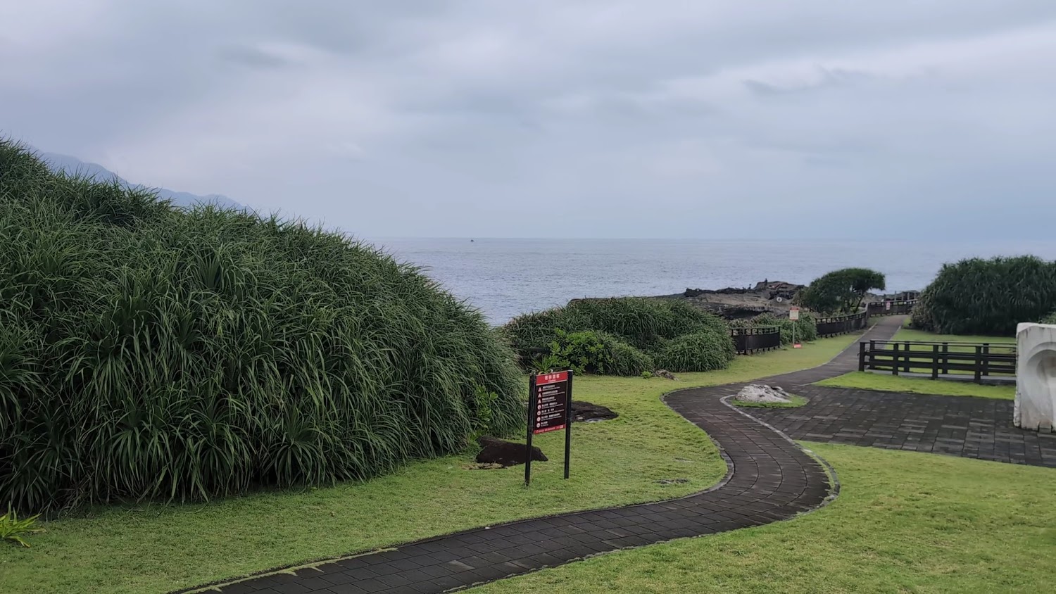 海邊公園與大片草地、步道通往海岸，遠方可見海洋與礁石