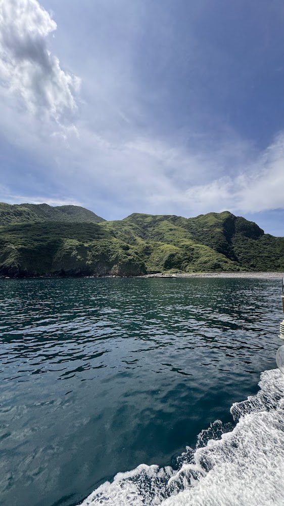 海面與遠方綠色山丘景觀