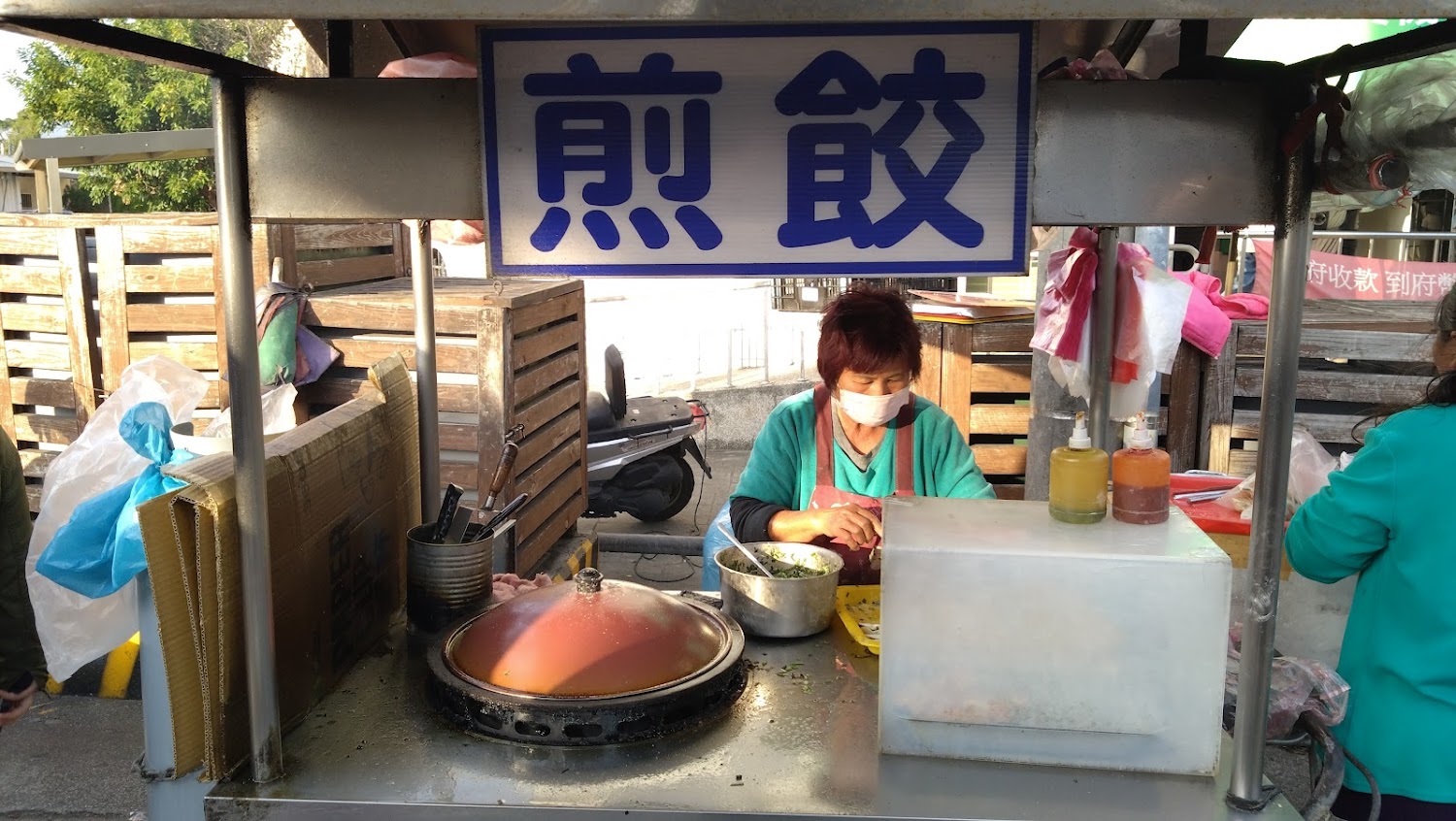 煎餃攤位現場製作,招牌上寫著煎餃