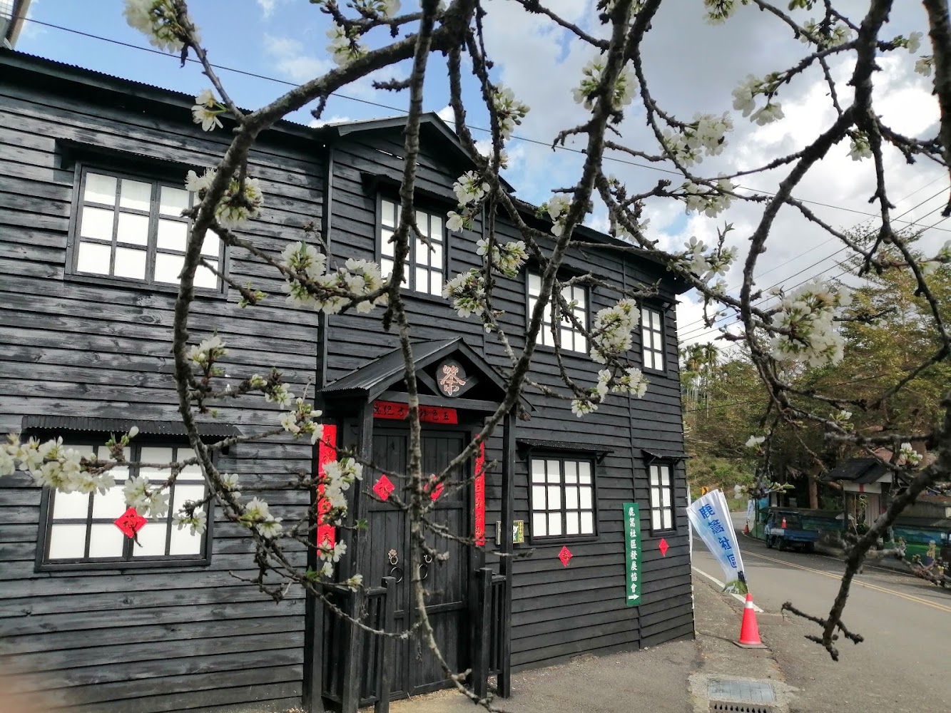 黑色木造建築與白色花朵樹枝
