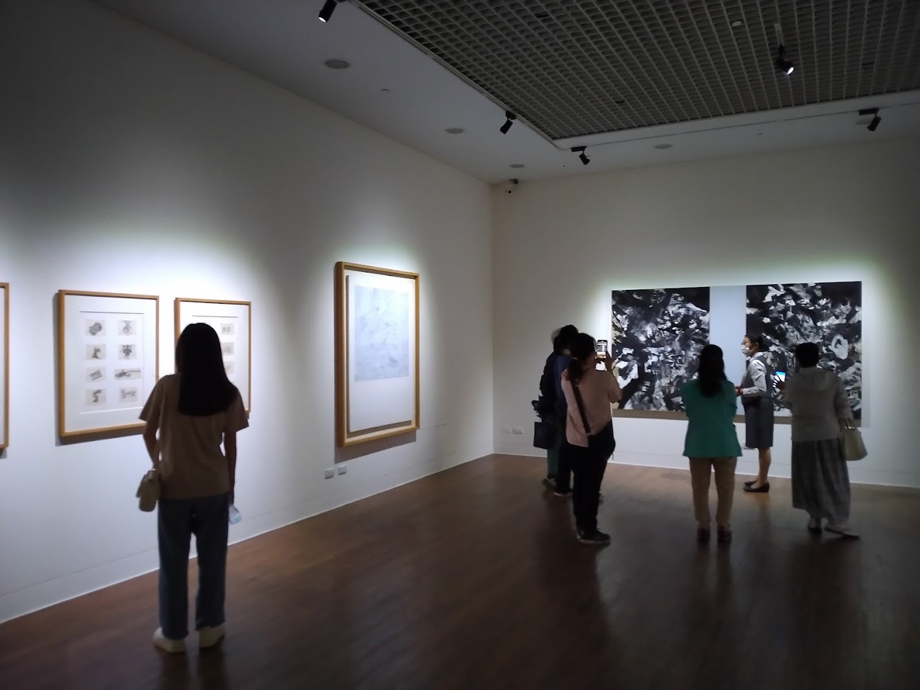 館內展牆陳列多幅畫作，民眾正在觀展