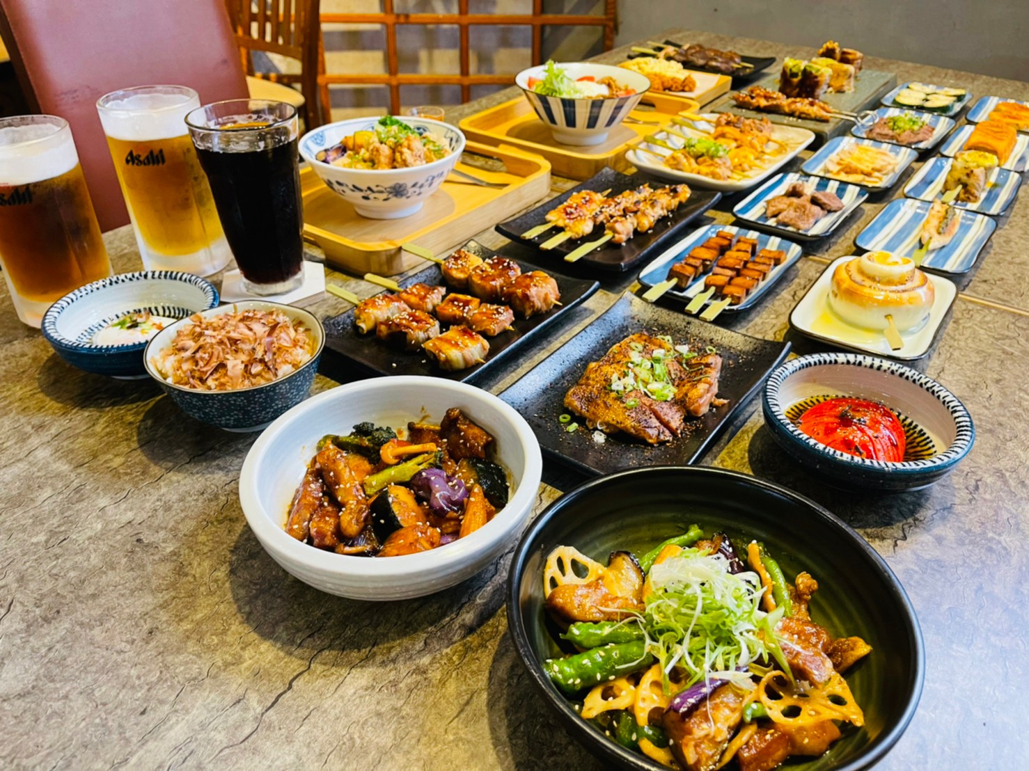 橫菁料理餐桌上擺滿各式串燒、炒菜與啤酒，豐盛的居酒屋饗宴