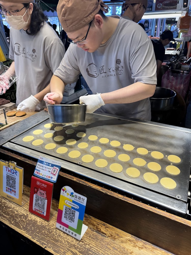 夜市攤販正在製作日式銅鑼燒,桌上放有多個麵糊餅皮。