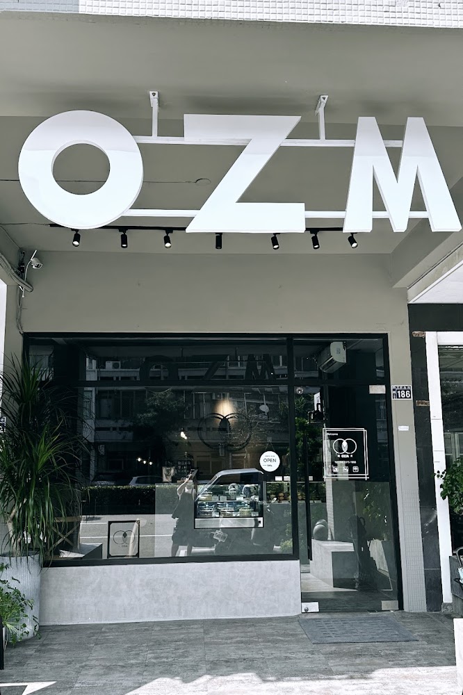 OZM啢男咖啡甜點外觀簡潔,門口有植物與透明玻璃窗