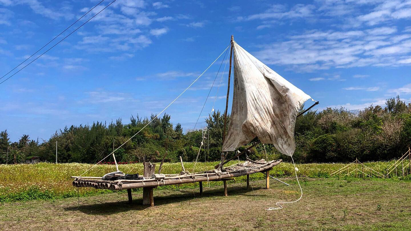 都歷部落阿美族傳統竹帆船停放草地，藍天白雲背景