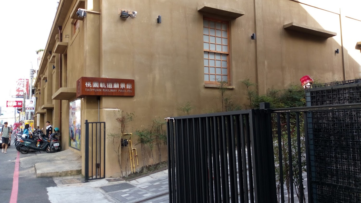 這張圖片主要是桃園軌道願景館的外觀,大樓外牆簡約且具現代感,並可見到標示牌和旁邊的機車停放區,沒有明顯的浮水印。