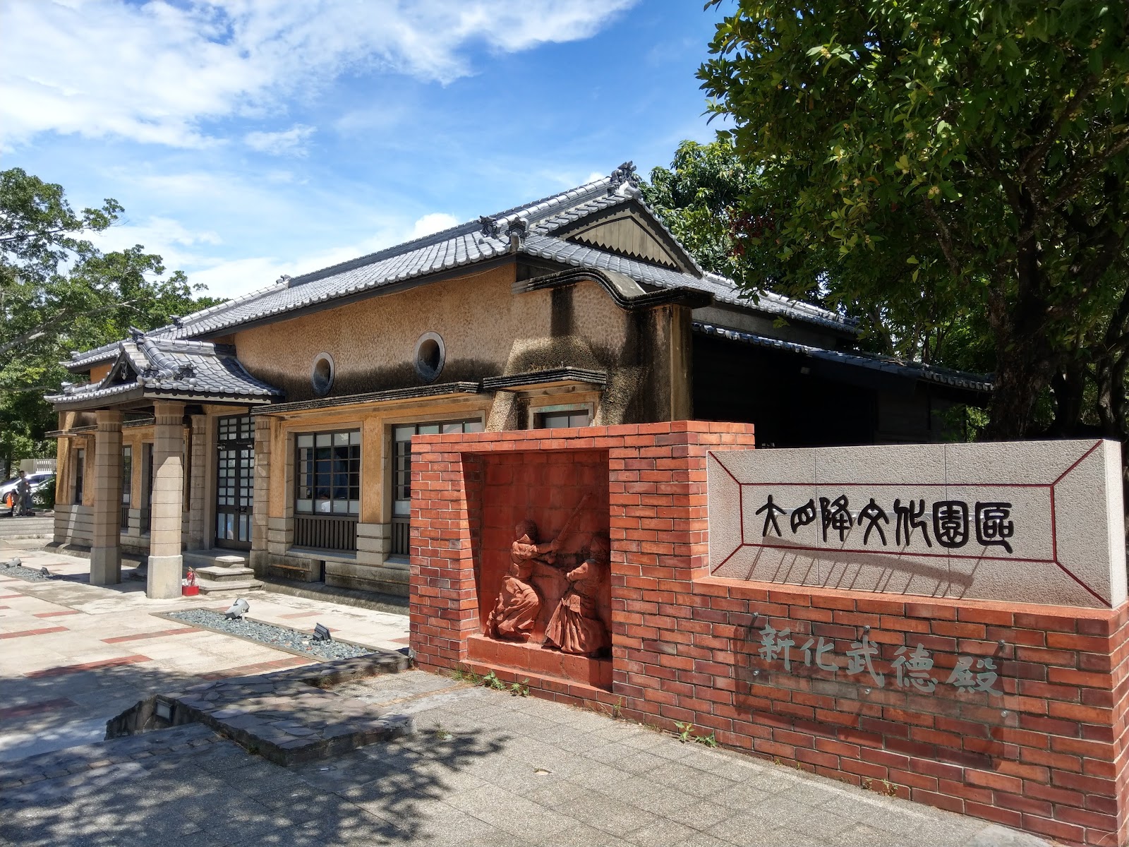 新化武德殿正面,日式黑瓦磚造建築,前方紅磚牌坊「大四障文化園區」