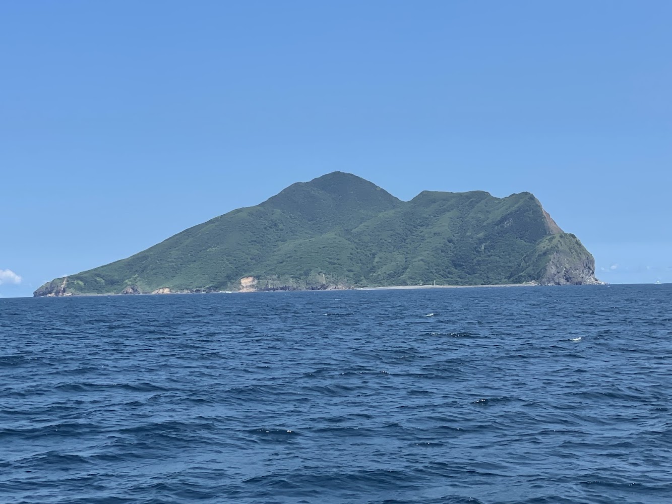 大海包圍著綠色龜山島，天空晴朗蔚藍
