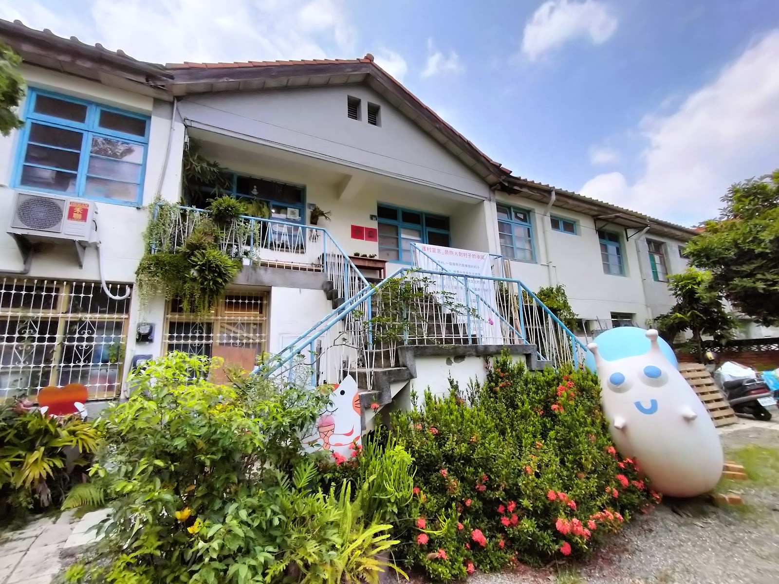 省府日常散策舊宿舍外觀,白色兩層樓建築,藍色窗框,庭院有可愛蛋型公仔裝置