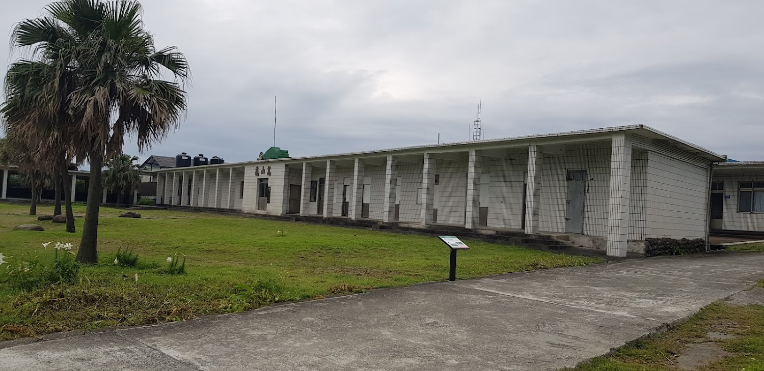 長型白色建築與草地棕櫚樹