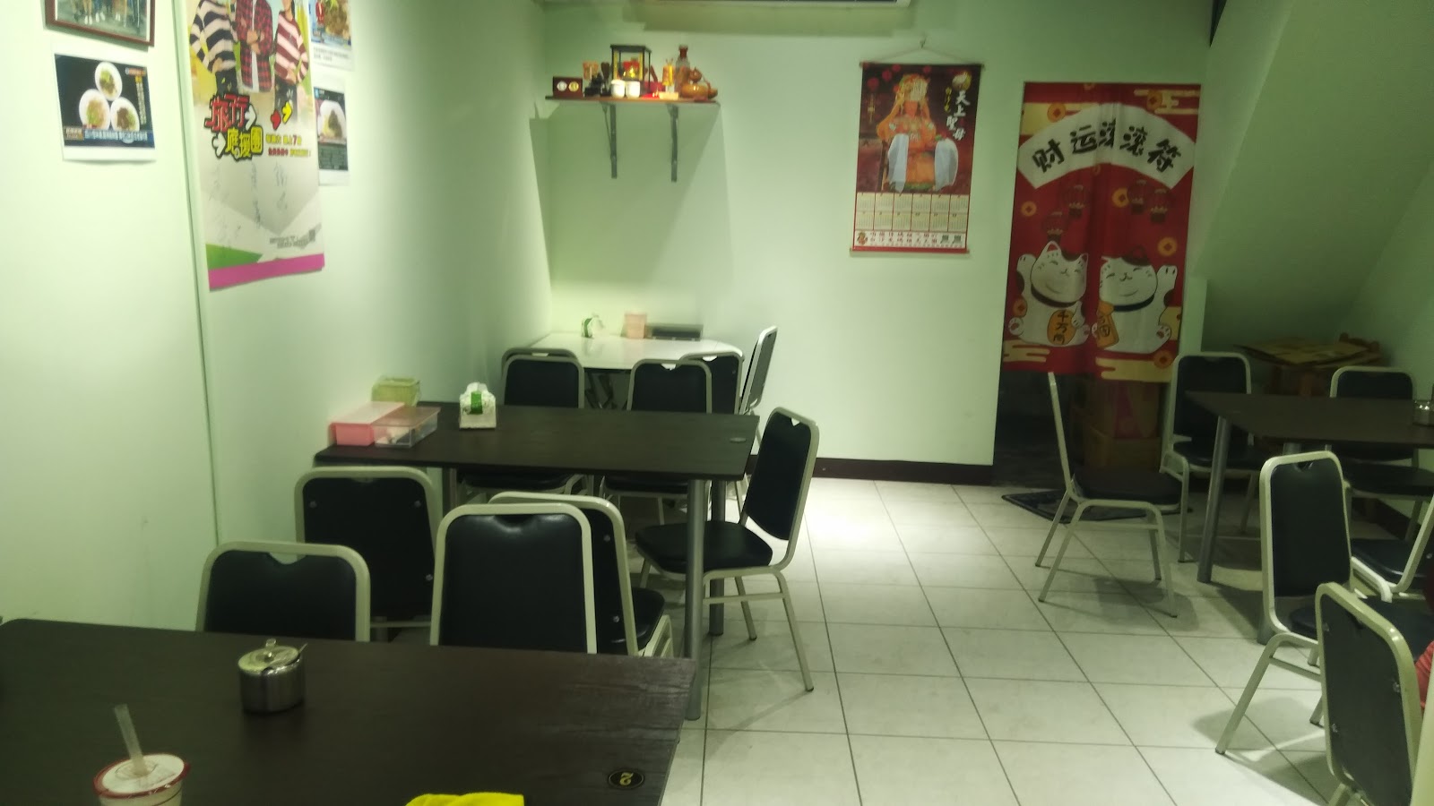 旭家私廚店內用餐空間，餐桌椅與牆上各式裝飾海報