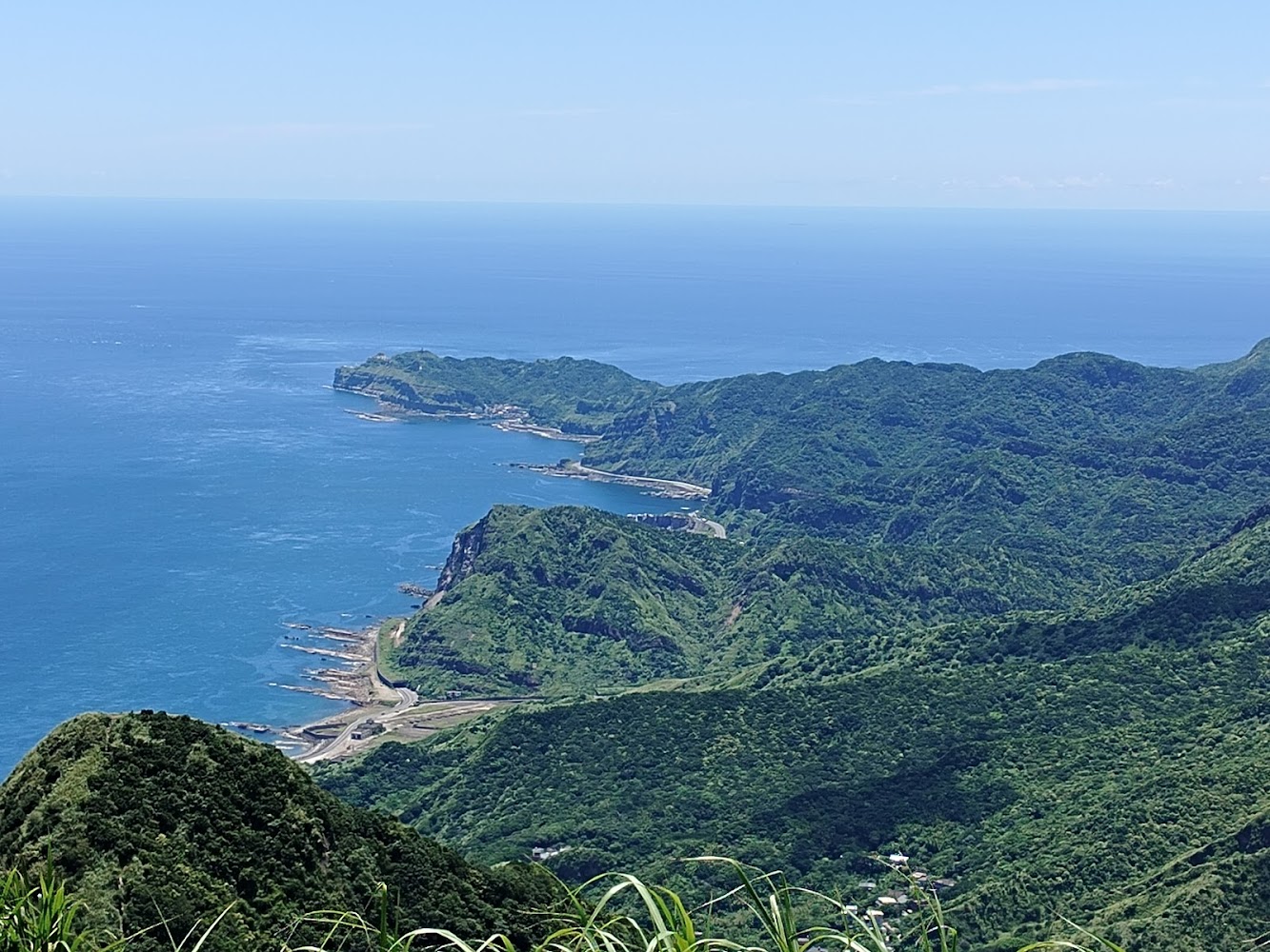 碧藍海洋與翠綠山脈相連的海岸線景色