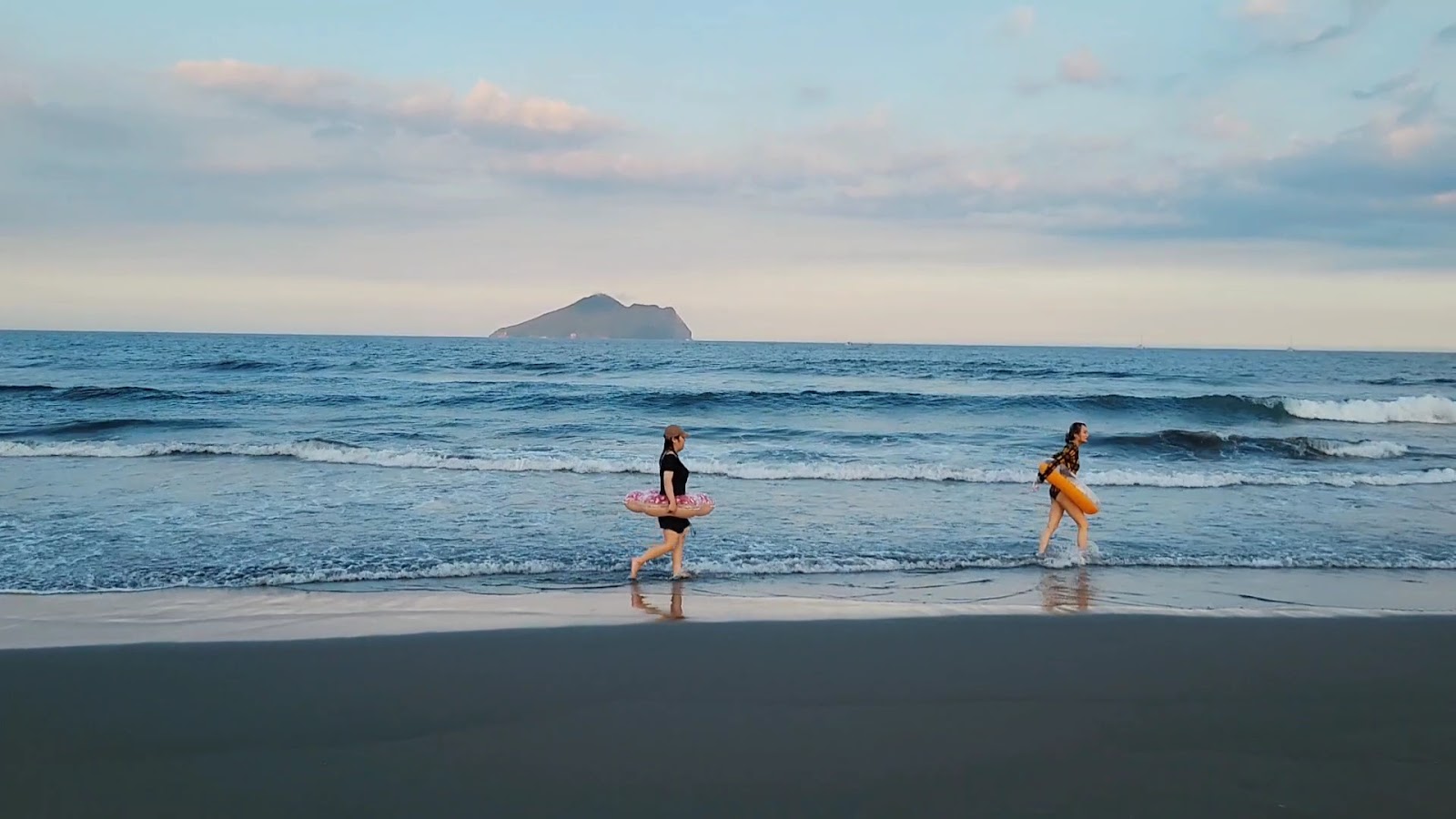 外澳沙灘黃昏龜山島，兩位女生抱游泳圈