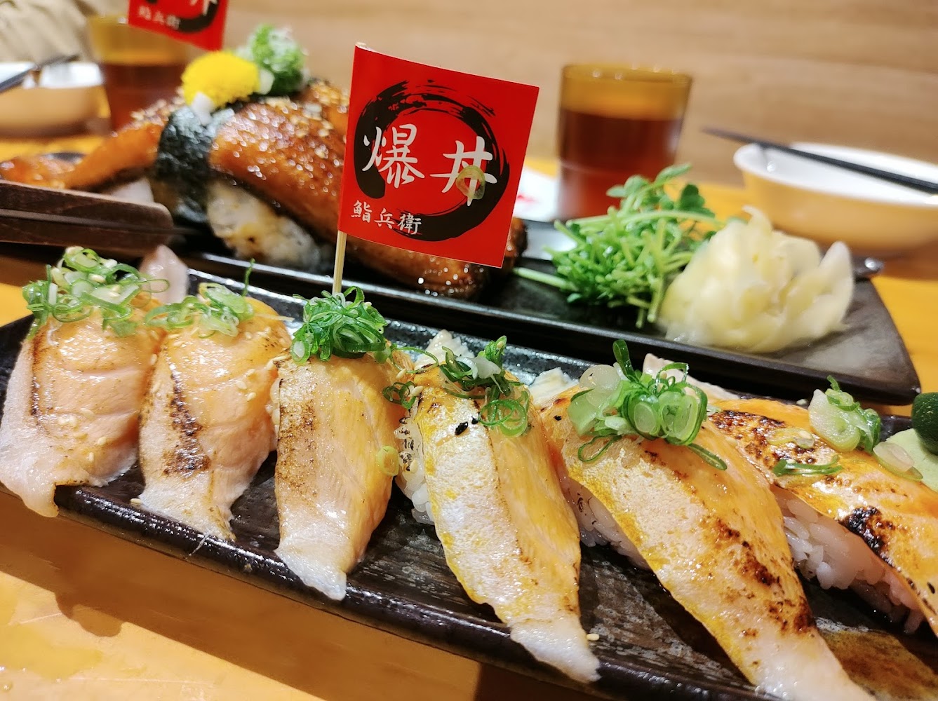 炙燒握壽司與鰻魚壽司,旁有薑片與小菜