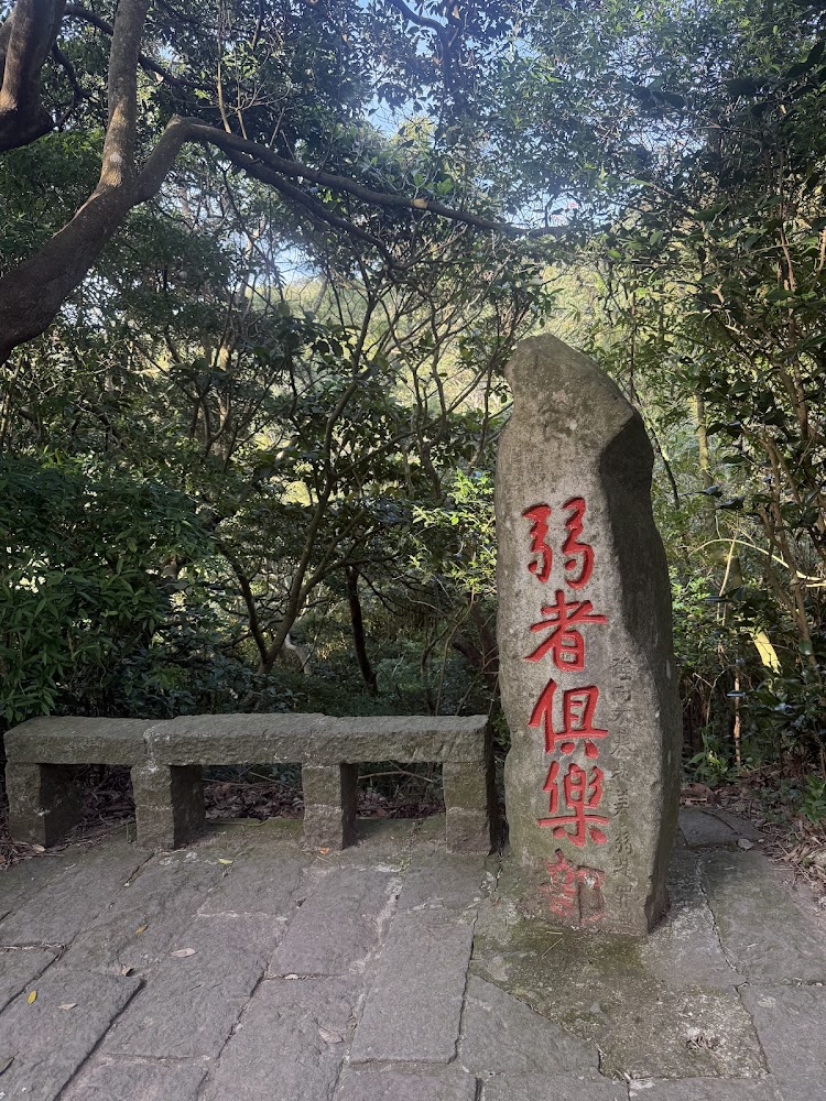 弱者俱樂部石碑，旁邊有休息石椅