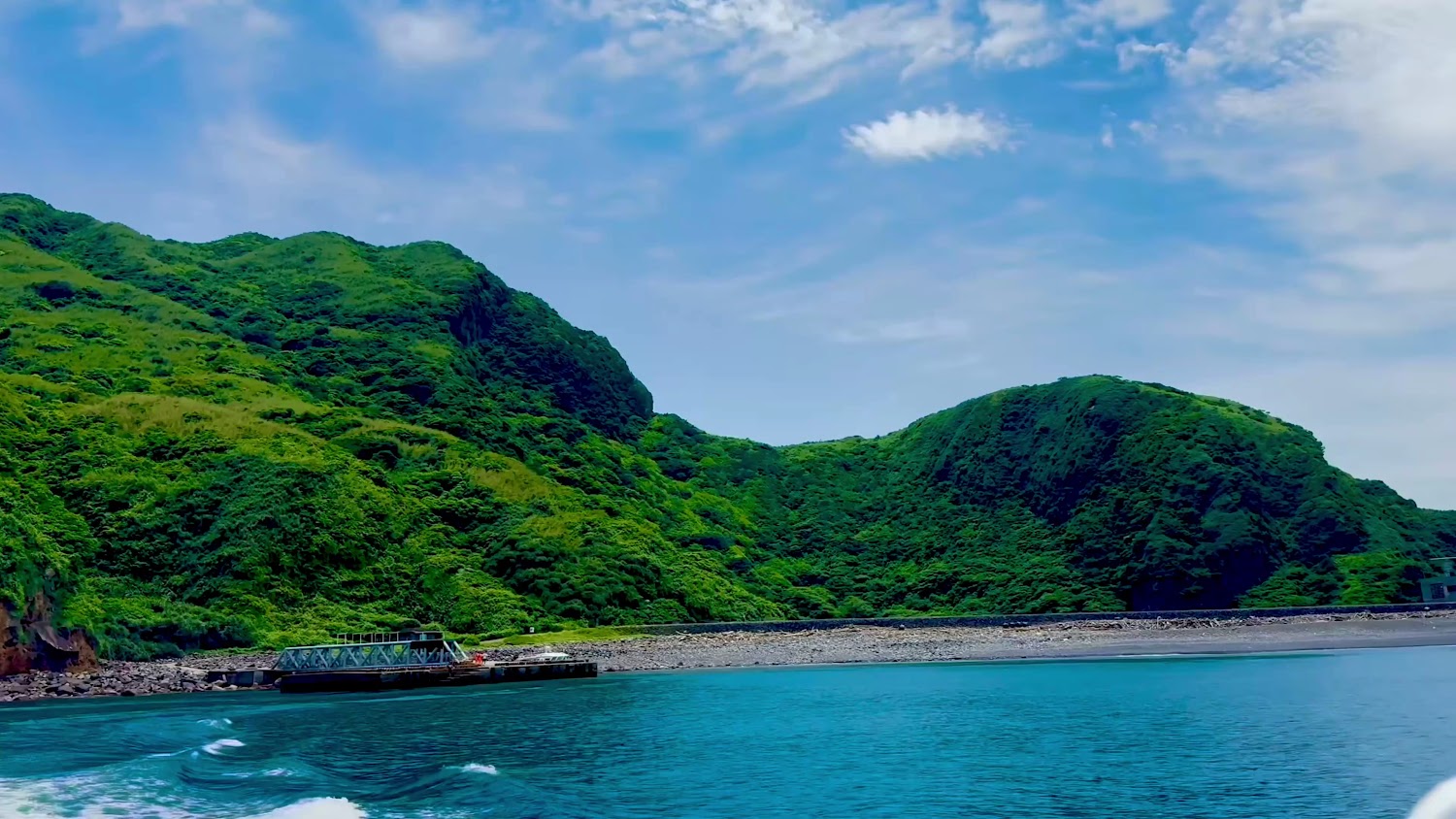 翠綠山丘海水與碼頭礁石景觀