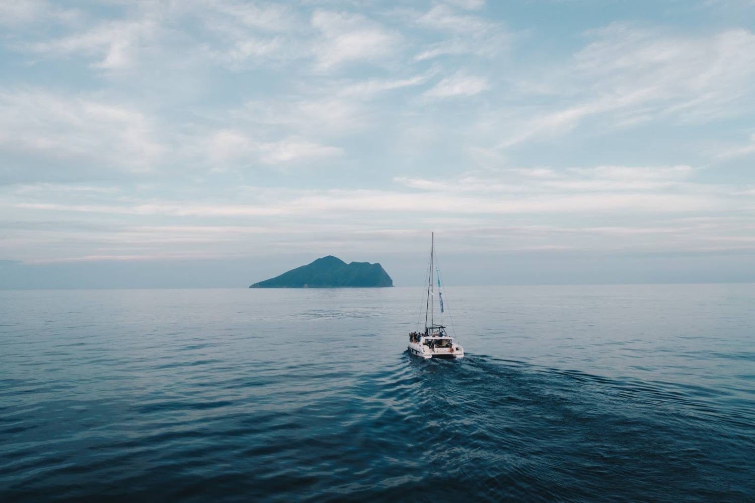 白色帆船航行於海面遠方可見龜山島