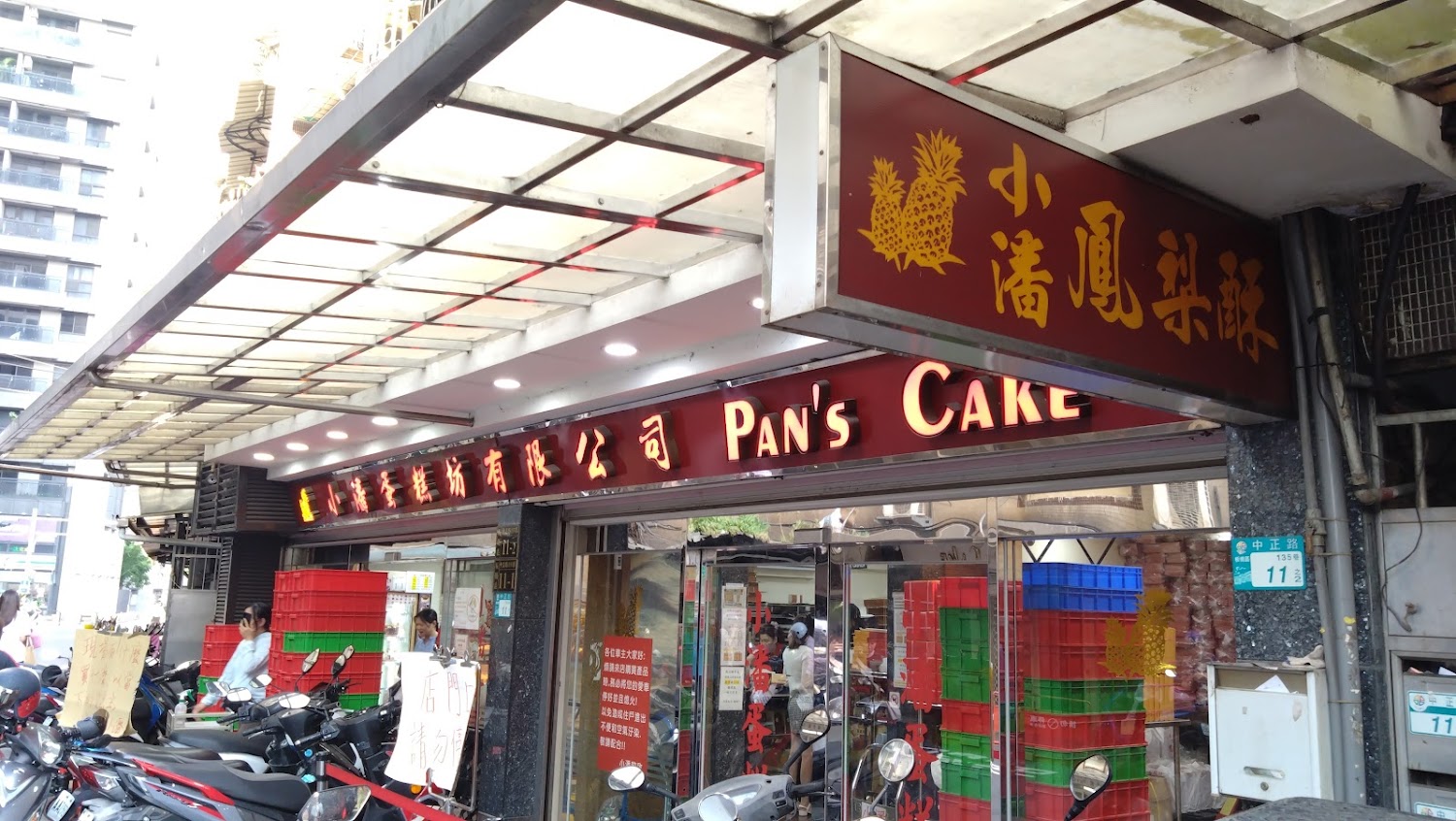 小潘鳳梨酥店門面，招牌顯眼，門口擺有塑膠箱與機車