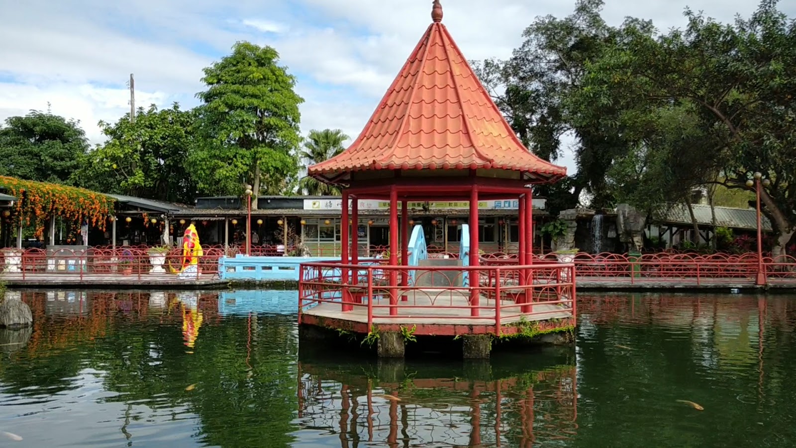 花蓮觀光糖廠紅色六角亭與池塘全景，背景有商店與藍天