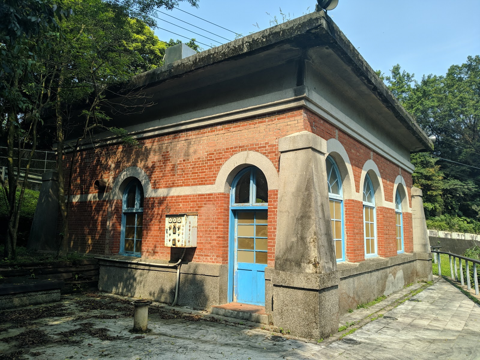 暖暖淨水廠百年幫浦間紅磚建築正面，拱形窗戶與藍色大門
