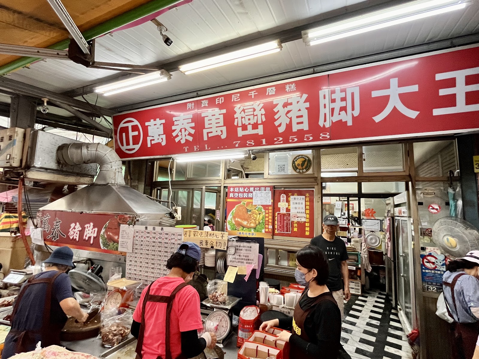 萬泰豬腳大王市場門面，工作人員忙碌切豬腳，招牌顯目