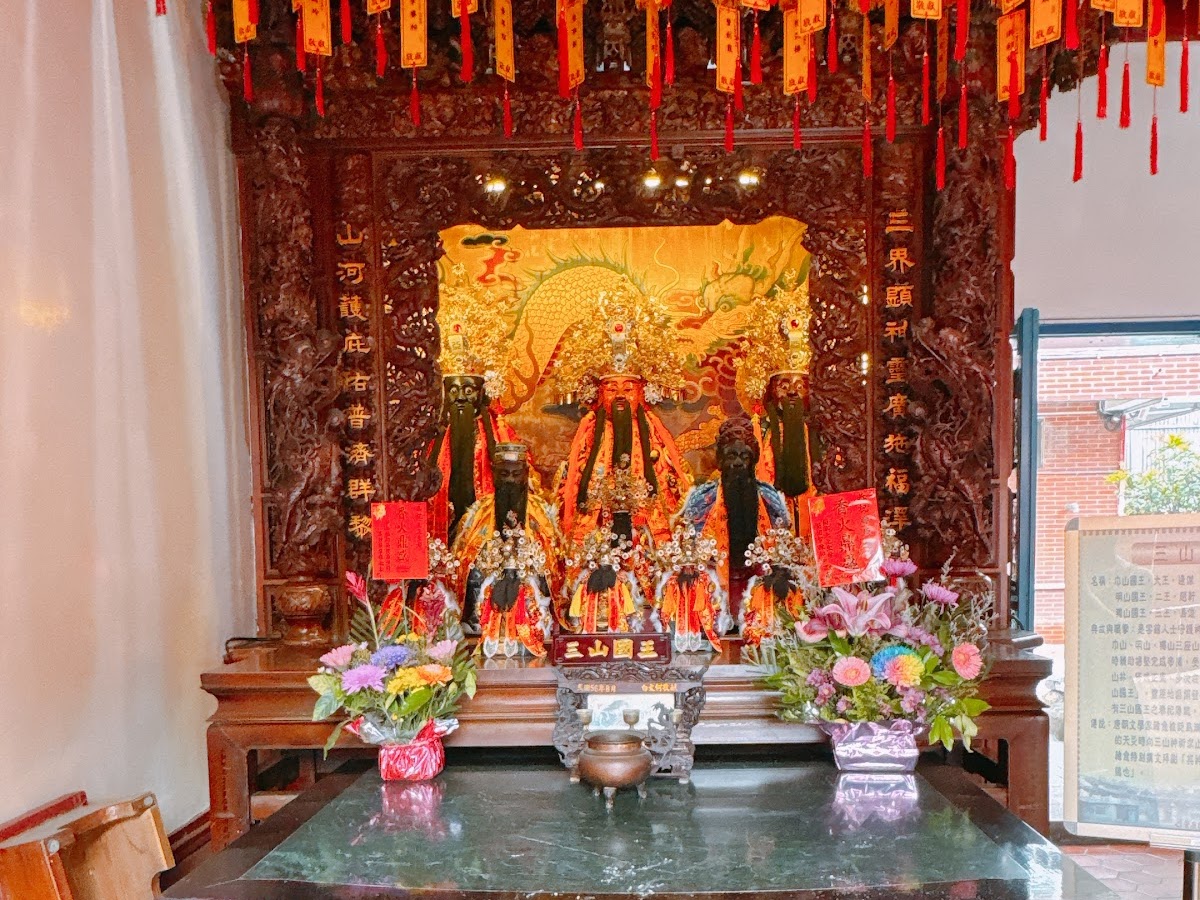 豐原慈濟宮三山國王神龕,天花板掛滿紅色祈福牌,供品花卉擺設