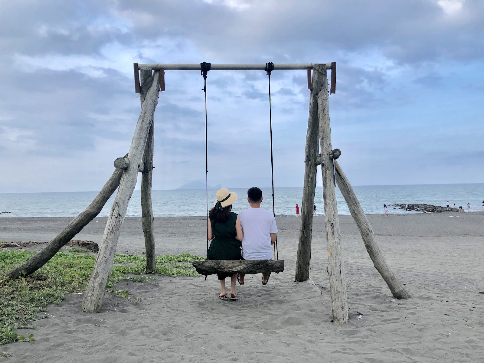 情侶並肩坐在壯圍海岸漂流木秋千上面向太平洋