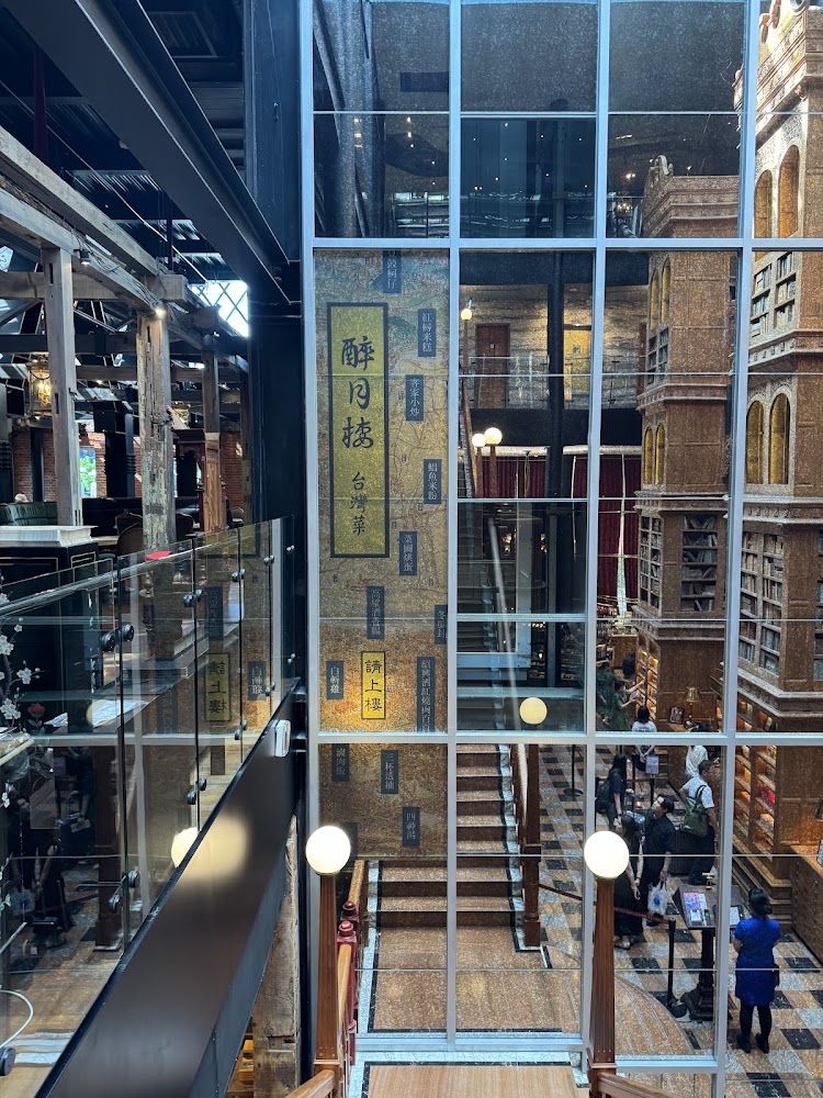 這張圖片主要展示了一個充滿書架與書本的建築內部，有透明玻璃牆和樓梯，牆上有『解⽉樓 台灣茶』等字樣，現場有人在參觀；未見浮水印。