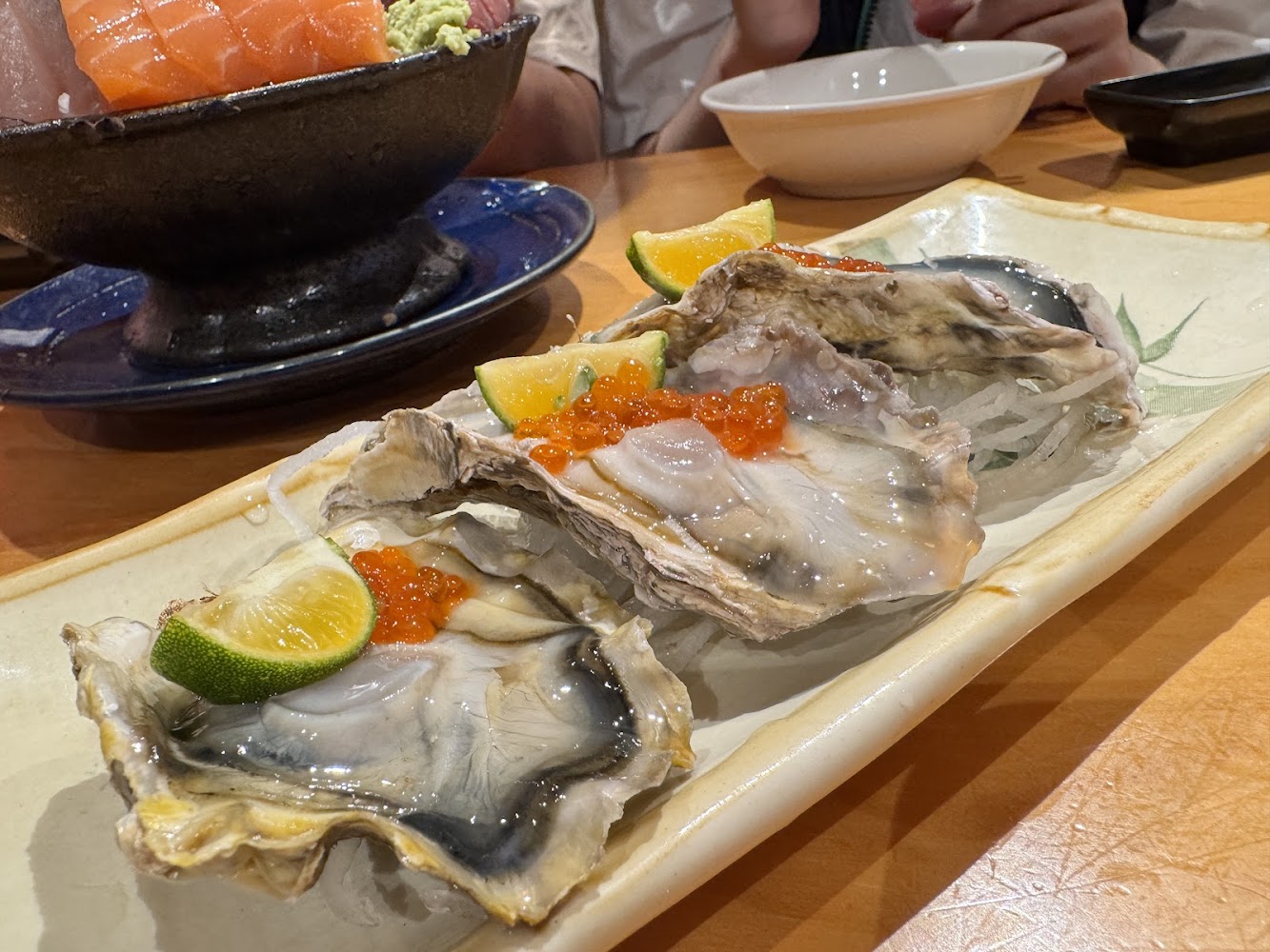 新鮮生蠔搭配鮭魚卵與檸檬片,旁邊有海鮮丼飯