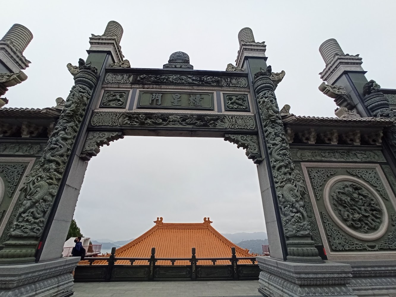 雕刻精美的傳統中式牌樓兩側有龍紋雕飾背景有寺廟
