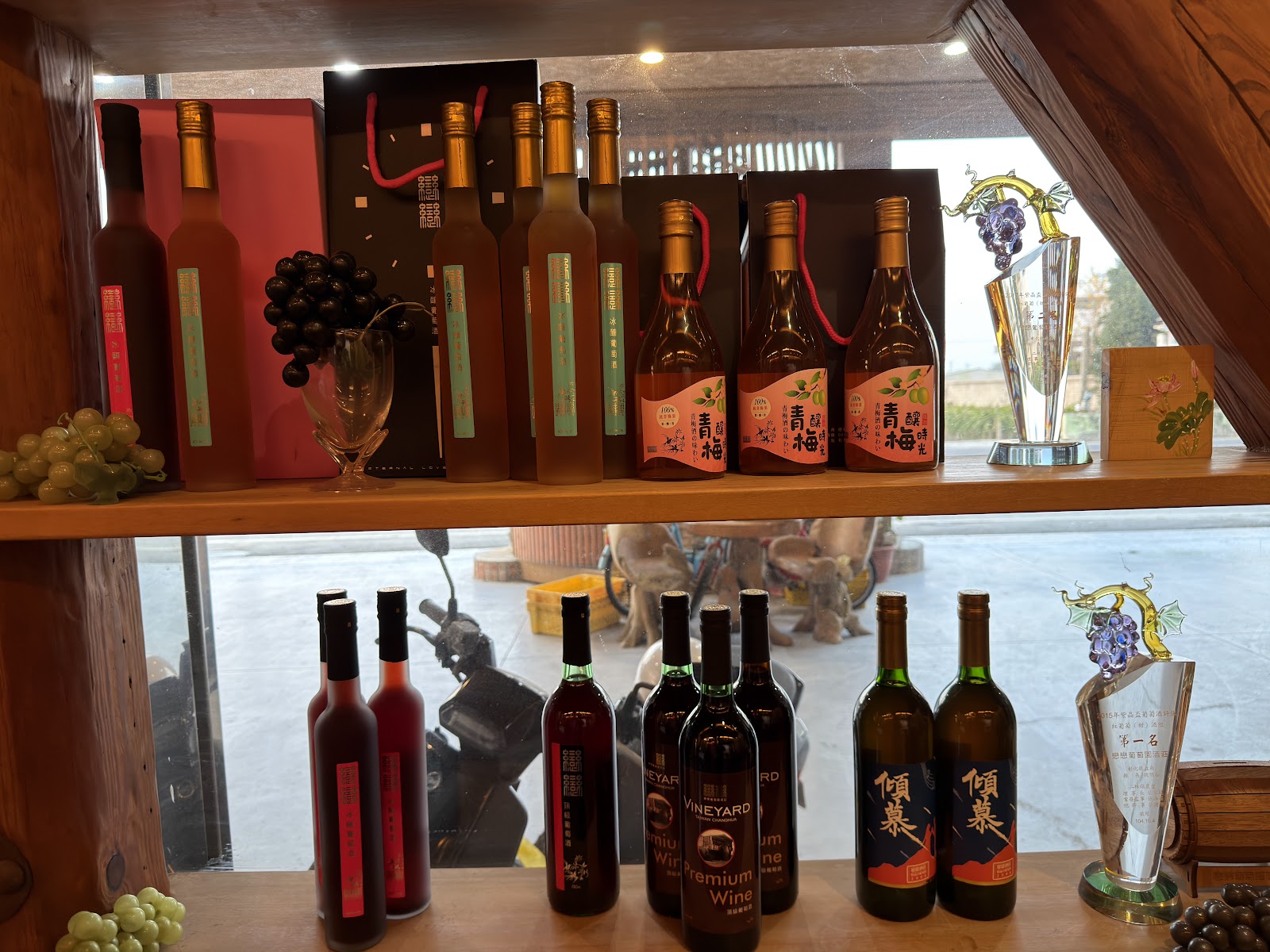 戀戀葡萄園酒莊展示架，陳列倾葉紅酒、青梅酒、VINEYARD Premium Wine 等自釀酒款，旁邊有獎盃