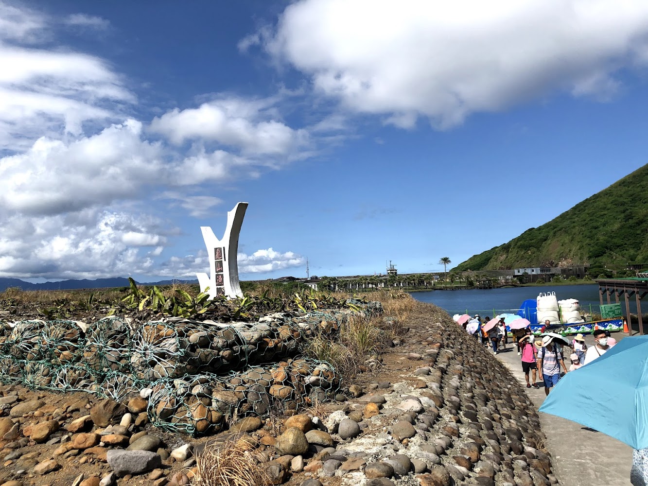 石堤步道白色地標與撐傘遊客