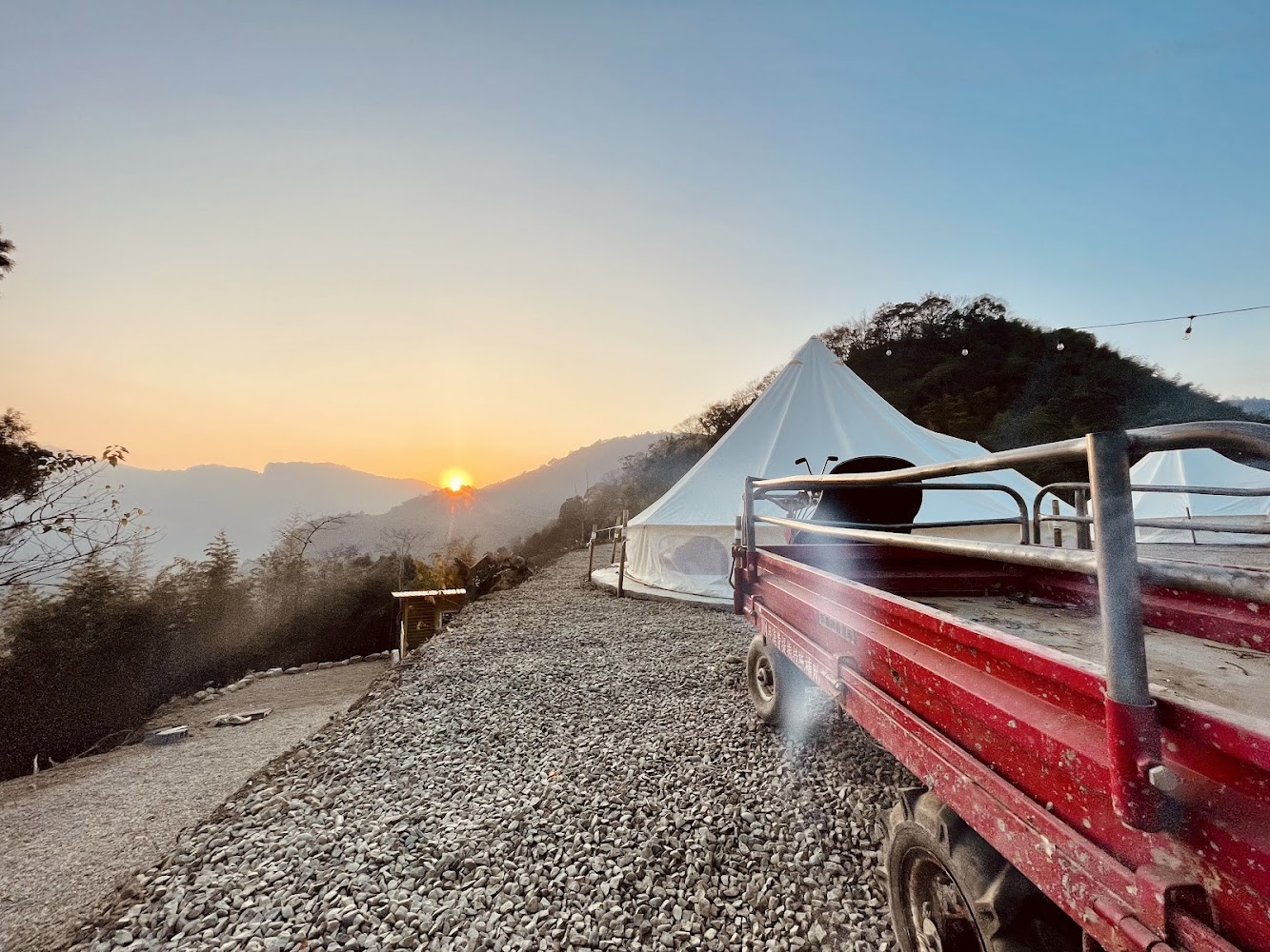 夕陽山景與白色帳篷及紅色小貨車