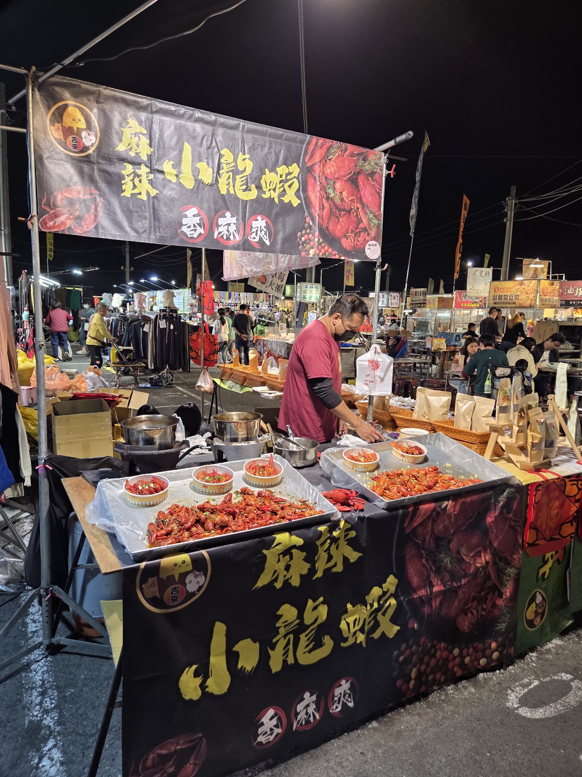 路竹夜市麻辣小龍蝦攤位,攤主展示鮮紅色小龍蝦,背景是夜市人群