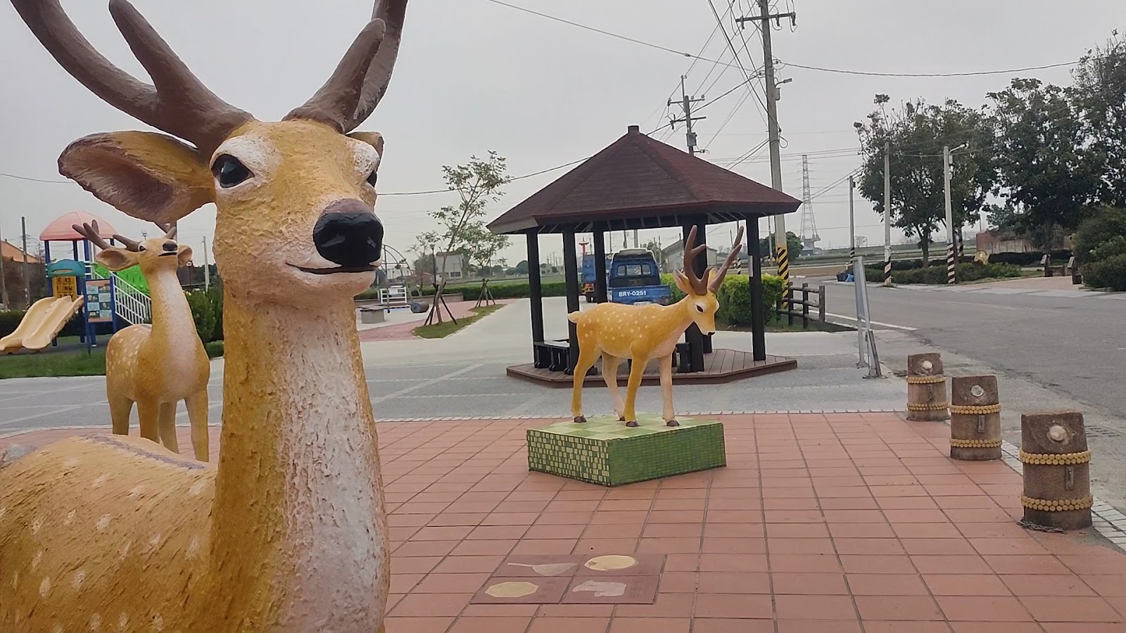 鹿北村廣場三隻梅花鹿雕像,近景大鹿仰頭,背景有涼亭和兒童遊樂場