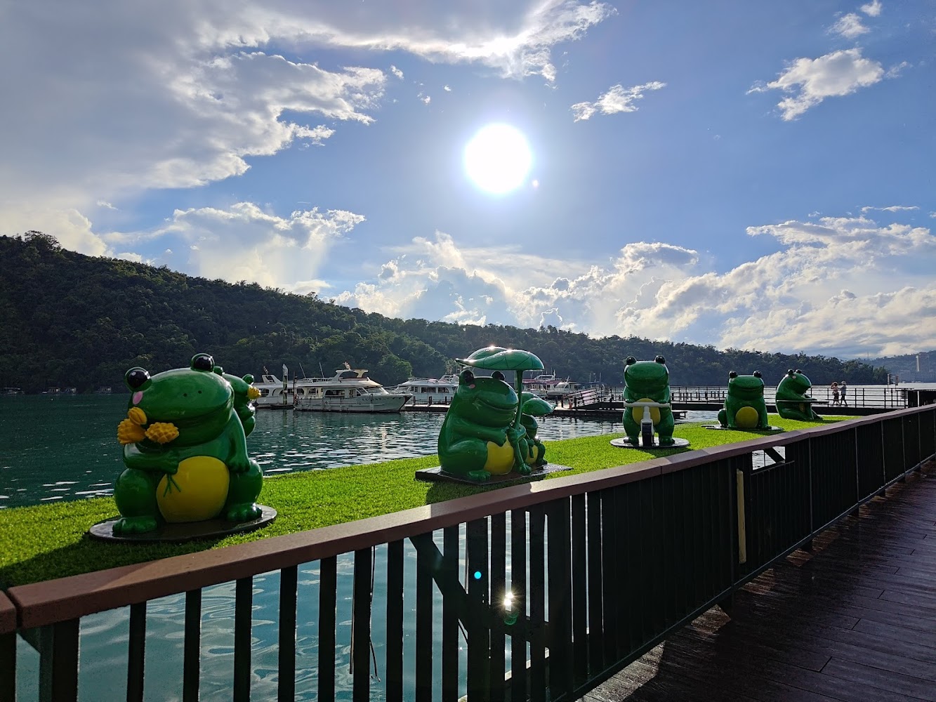 湖邊棧道上的青蛙雕像與遊艇山景
