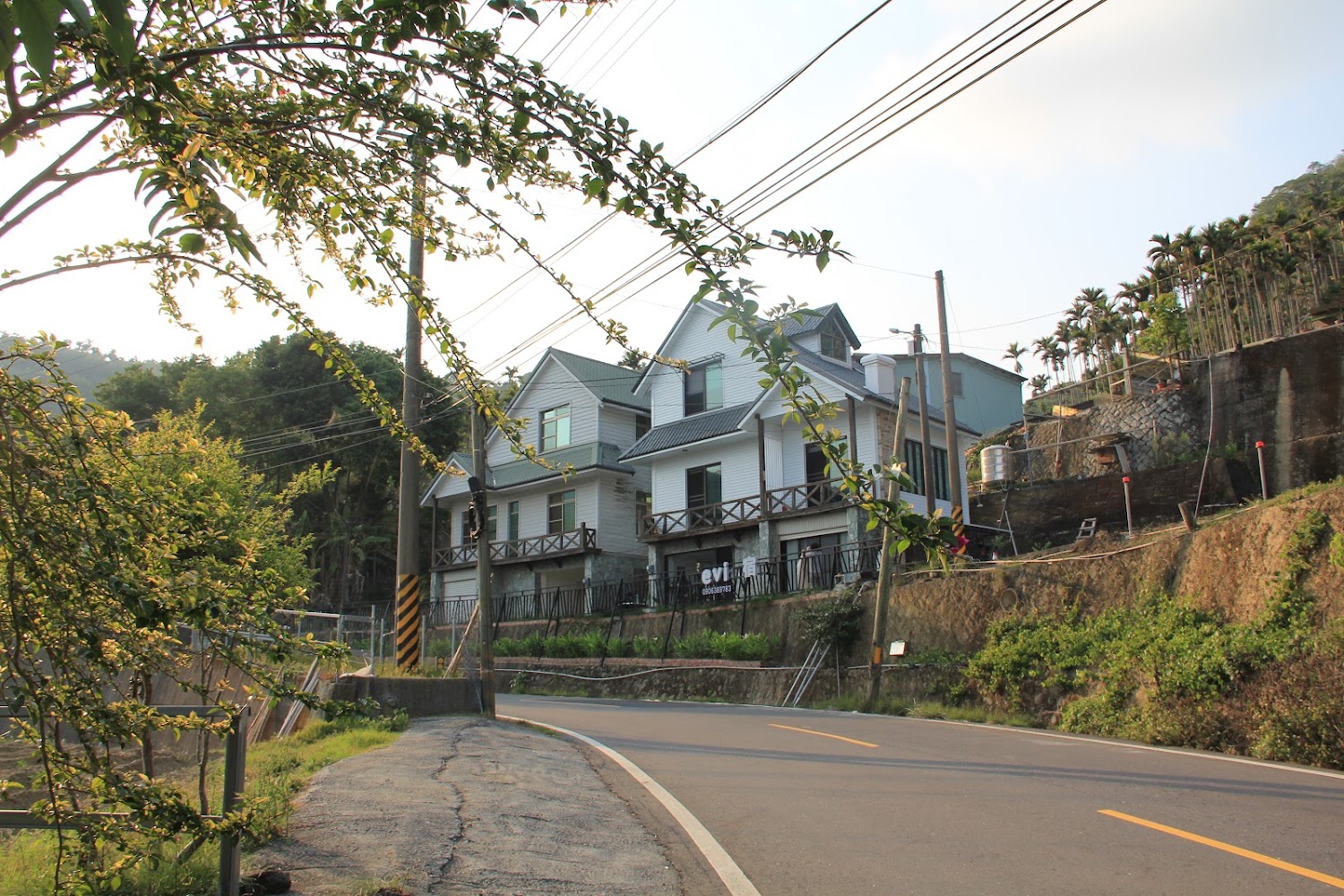 山區彎道旁的現代白色建築,前方有樹木與山坡梯田