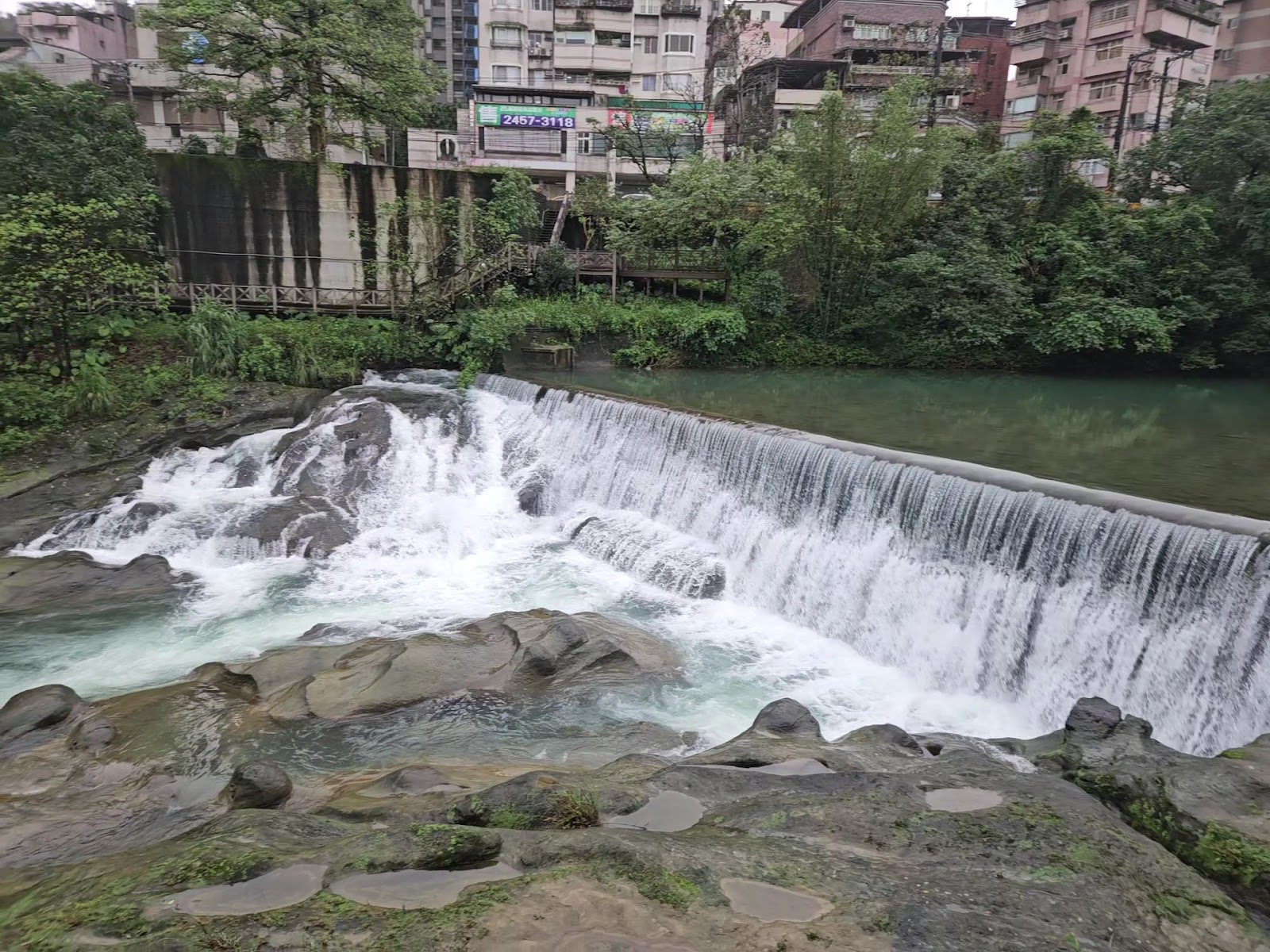 暖暖溪旁小瀑布，市區高樓背景與自然溪流形成對比