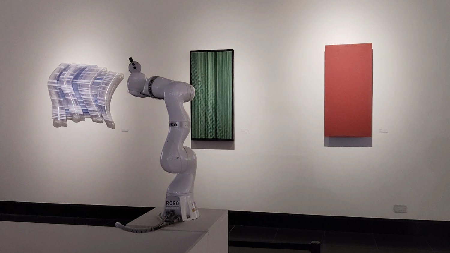 機械手臂在展場內與抽象畫作共構的畫面