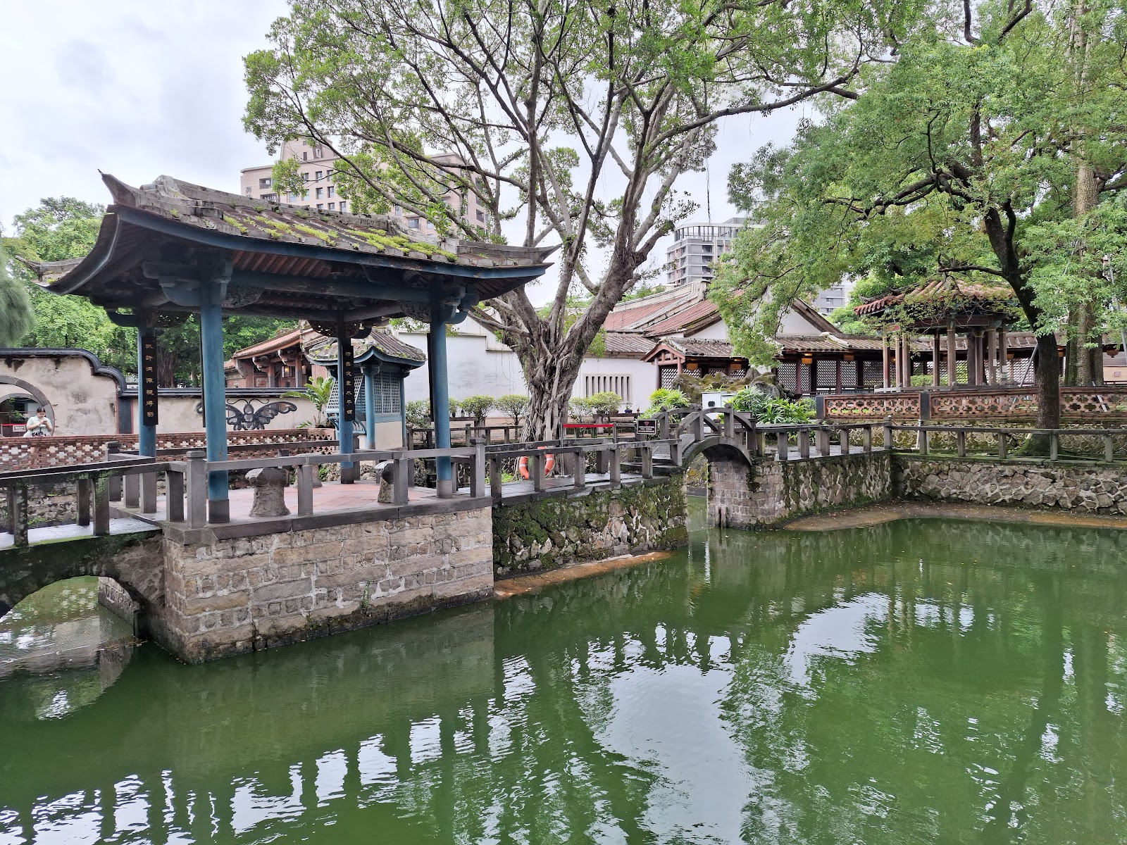林本源園邸庭園全景，藍色圓柱涼亭、石拱橋、綠色水池，新北板橋一日遊景點