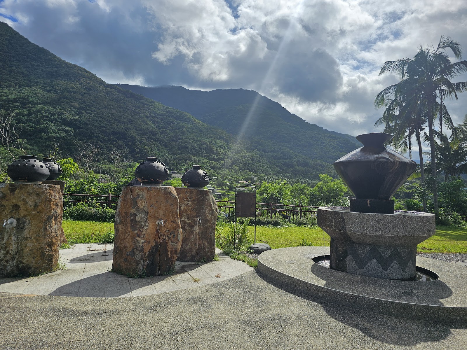 嘉蘭溫泉公園廣場,原住民陶壺造型裝飾物矗立石座之上,青翠山脈為背景