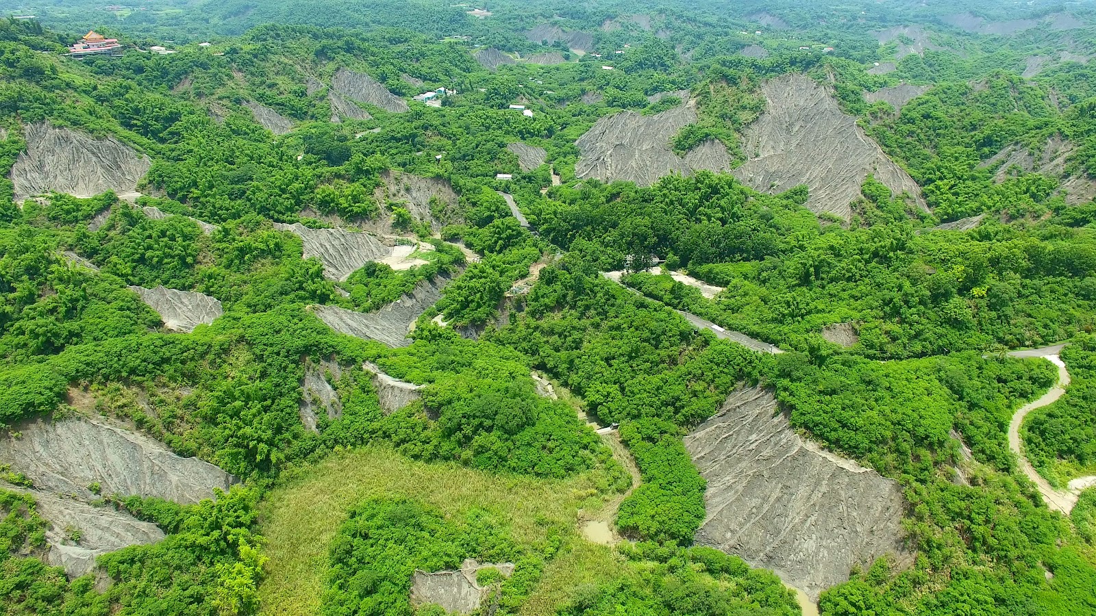 台南龍崎牛埔惡地空拍俯瞰，灰白泥岩地形與翠綠植被交錯分布的壯觀景象
