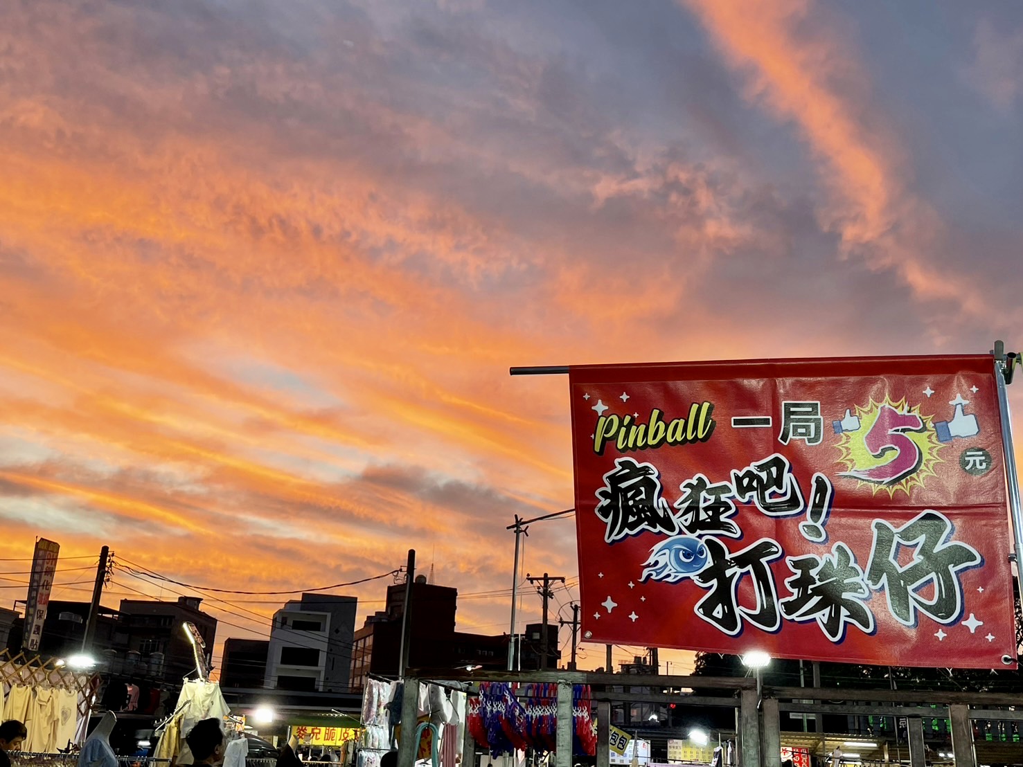 路竹夜市夕陽美景，橘紅色天空搭配打球仔遊戲招牌，夜市熱鬧氛圍
