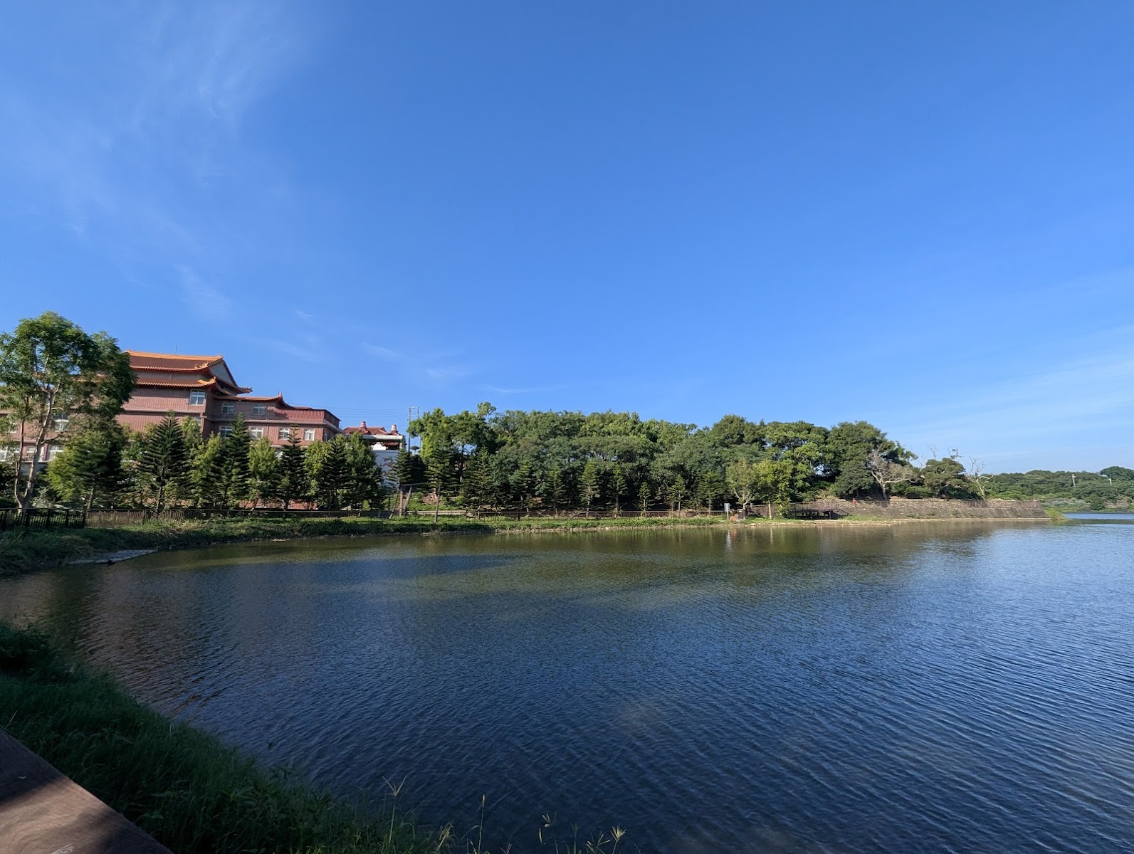 苗栗造橋龍昇湖湖面倒映左岸宮廟建築，清晨靜謐如鏡