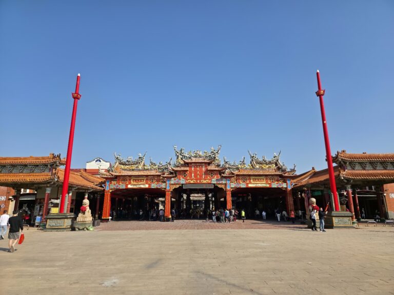 南鯤鯓代天府廟門正面全景,兩側高聳紅色旗竿,台南北門廟宇