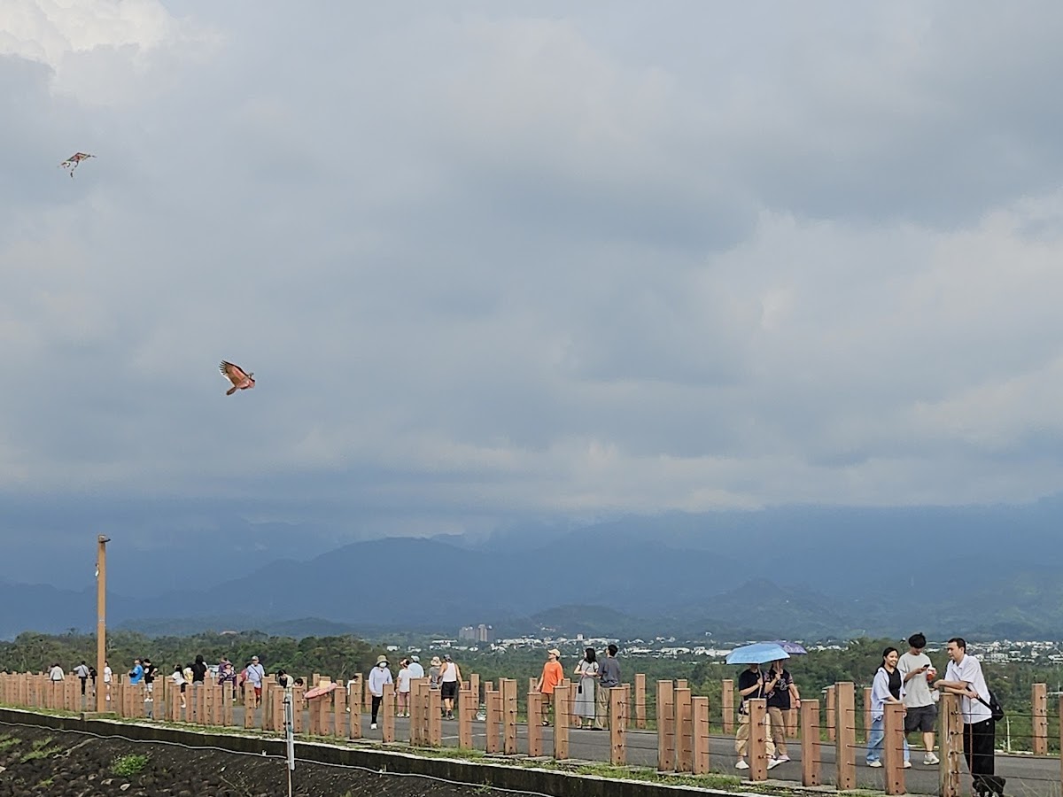仁義潭水庫紀念碑區域，堤頂步道俯瞰遊客與遠景山城